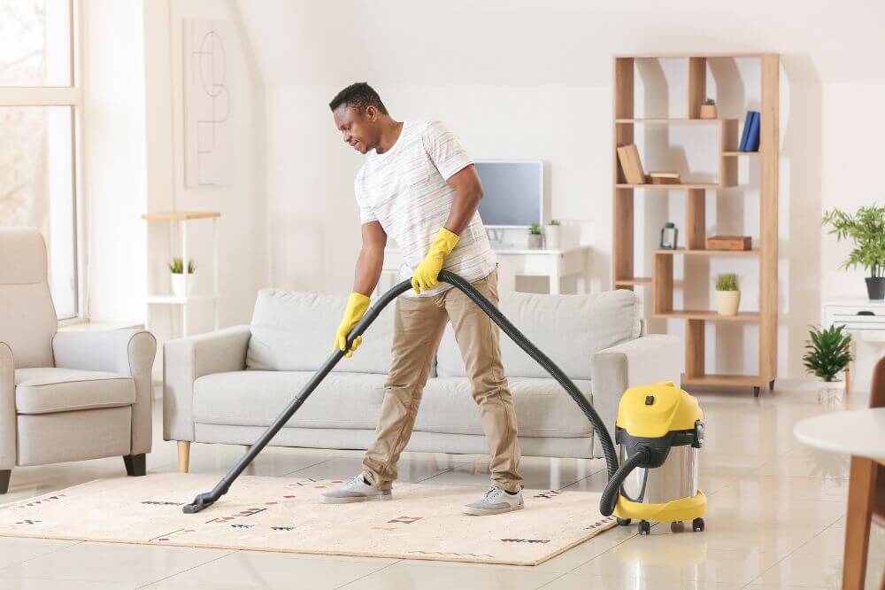 Man hoovering and organising his new home after moving 